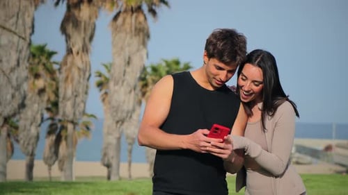 Happy Couple Looking at Phone on Sunny Day