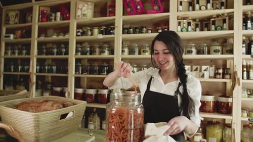 A Young Woman Shop Assistant Working in a Zero-Waste Store or Shop