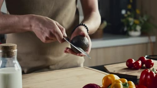 Man Cutting Avocado While Preparing Meal in Kitchen