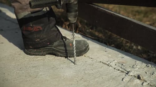 Builder Drills a hole in the wall with a Hammer Drill. Close-up of hammer drill perforator making ho