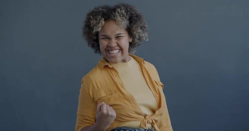 Slow Motion Portrait of Excited African American Woman Expressing Joy Celebrating Good News on Grey