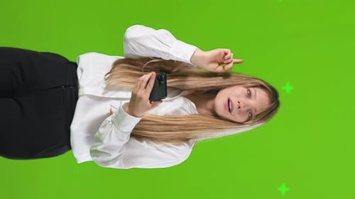Smiling Woman Points with Phone on Green Screen