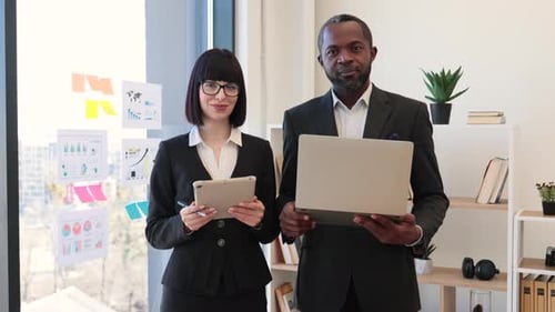Business Professionals Smiling With Laptop and Tablet in Office