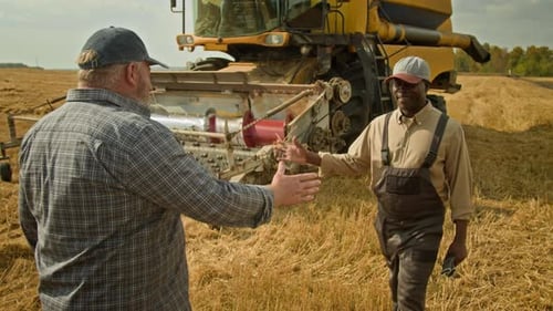 Two Smiling Farmers Shaking Hands in Wheat Field