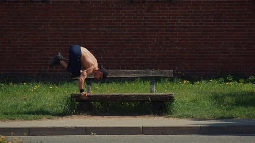 Young Muscular Man on Bench Doing Leg Raises and Handstand Pushups Concept of Responsible Attitude