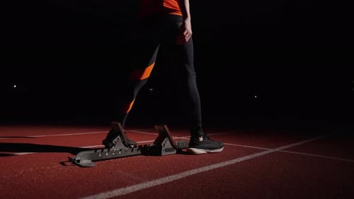 Athletischer Mann in Sportkleidung trainiert alleine auf der Laufstrecke im Stadion Läufer beim Start Zeitlupe