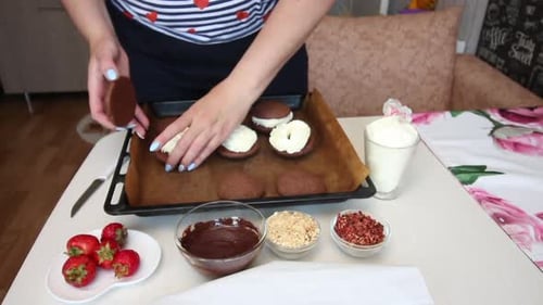 Woman Assembling Chocolate Cookies with White Frosting