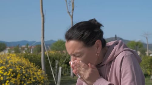 Woman Sneezing and Blowing Nose in Outdoor Park
