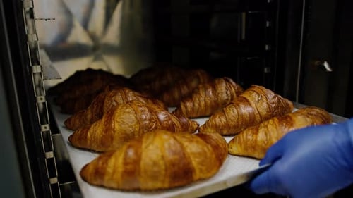 Kitchen in the bakery - ready-made croissants are taken from the oven