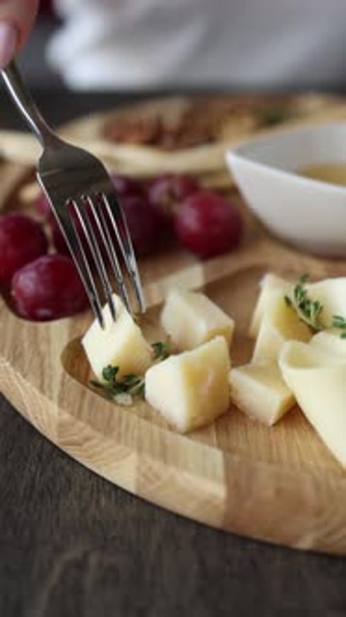 A dish of sliced hard cheese, nuts, honey, and grapes. Close up