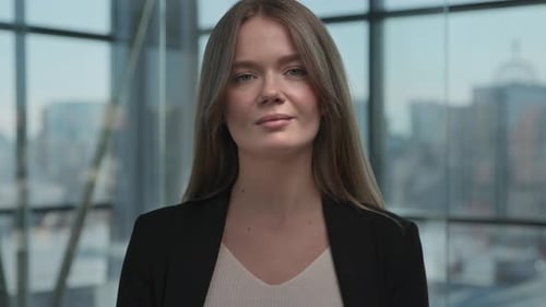 Confident young businesswoman in formal suit smiling at camera in modern office