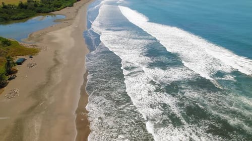 Aerial view of long sandy beach with turquoise ocean waves
