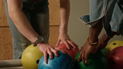 Vielfältige Frauen und Männer wählen Bowlingkugeln von Rack