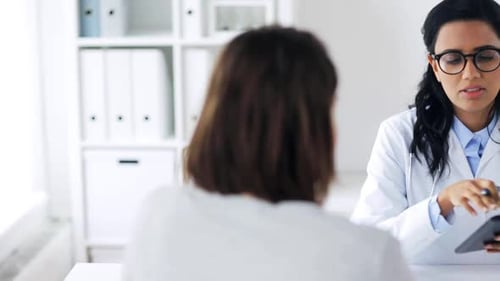 Doctor and patient discussing test results on tablet in hospital room