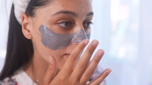 Woman Applies Shiny Face Mask in Bright Home