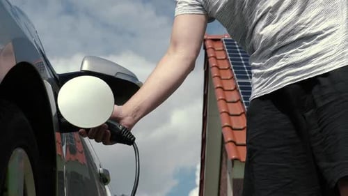 Electric Car Being Unplugged with Solar Panels