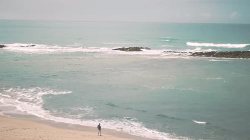 Ein Mann steht alleine am Strand und schaut aufs Meer