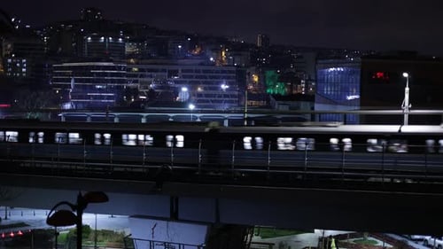Die U-Bahn fährt nachts vor dem Hintergrund der Stadt. Licht aus dem Fenster des Zuges c