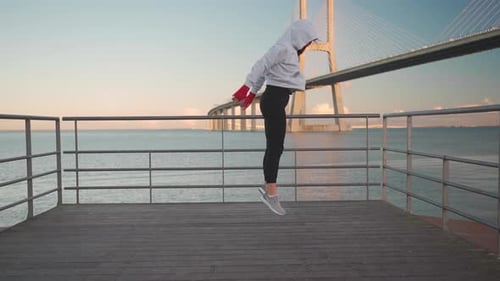 Femme kickboxeuse athlétique en sweat à capuche faisant des burpees sur la jetée