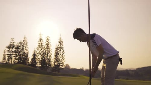 Golfer Putting on Green at Sunset