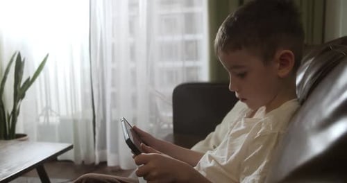 Boy Using Tablet on Couch at Home