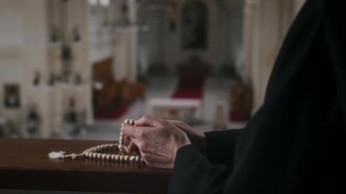 Hands Hold Rosary Beads in Church