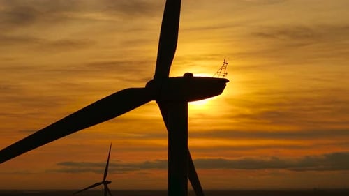 Nahaufnahme einer Windmühle, die sich vor dem Abendhimmel dreht, rotierende Turbine, die erneuerbaren Strom erzeugt