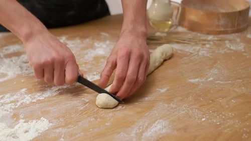 Baker Cutting Dough Into Pieces on Table