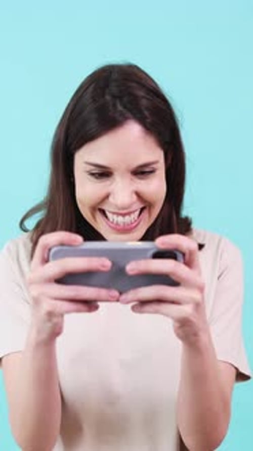 Woman Playing Mobile Game on Turquoise Background