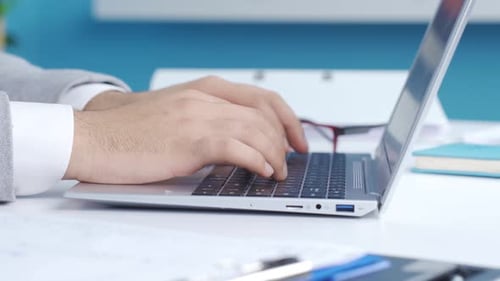 Fingers typing on keyboard on laptop in close-up office.