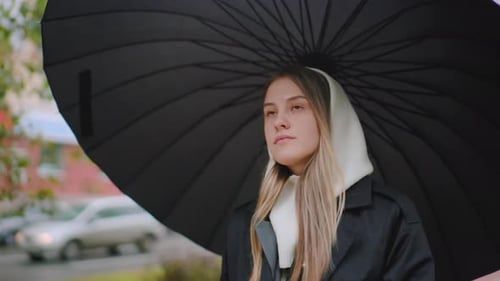 Young Woman Under Umbrella Walking on Rainy Day