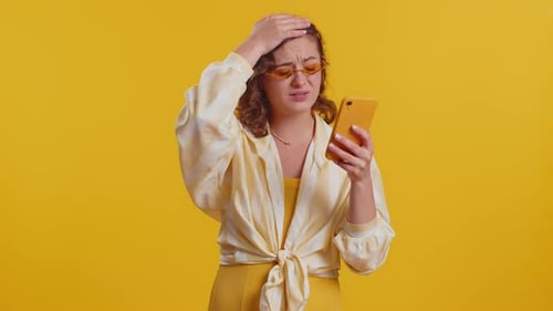 Woman Looks at Cell Phone with Confusion