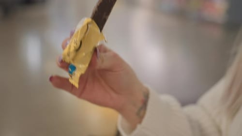 Elegant Woman Eating Chocolate Biscuit From Sachet on Bench