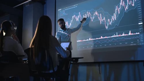 Man Presents Financial Data to Women in Office