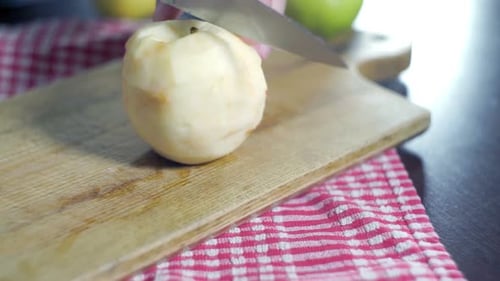 Chef slicing fresh organic apple on wooden plank preparing healthy snack in kitchen