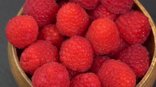 Ripe raspberries close up rotate in a wooden bowl. Juicy fresh raspberry berry is healthy