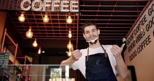 Content Young Guy Smiling During Work in Coffee Shop