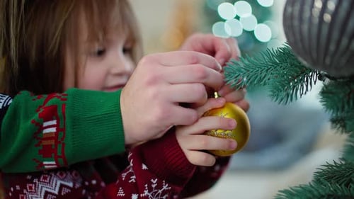 Child Decorating Christmas Tree with Shiny Ornament