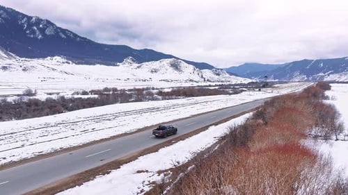 Black Pickup Truck Driving on Snowy Mountain Road in Winter
