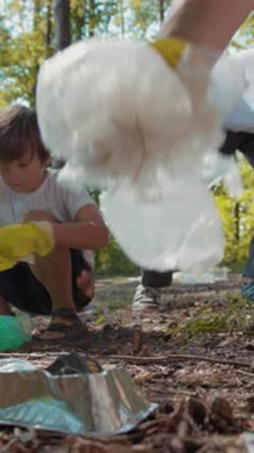 Child and Adult Picking Up Litter in Forest