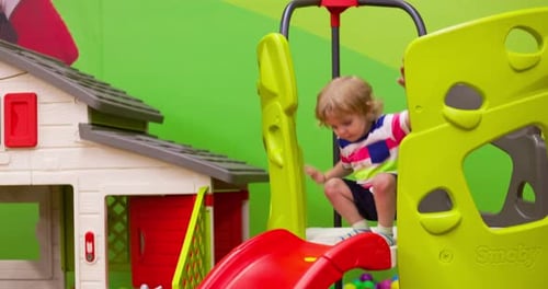 Petit garçon à cheval sur un toboggan au centre de jeux intérieur