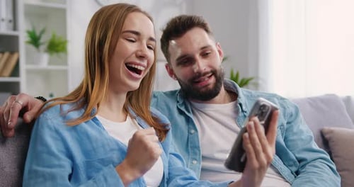 Couple Relaxing and Celebrating with Smartphone