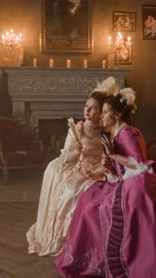 Two women in rococo gowns indoors