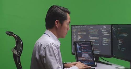 Developer Working With Tablet While Write Code With Multiple Screens In Green Screen Studio