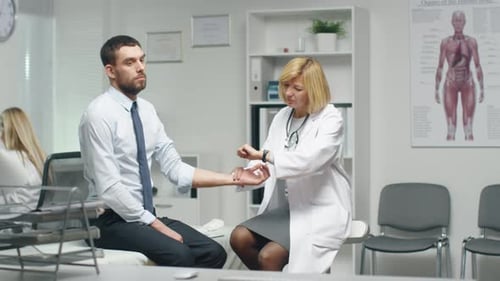 Mid Adult Female Doctor Manually Checks Male Patient's Pulse.