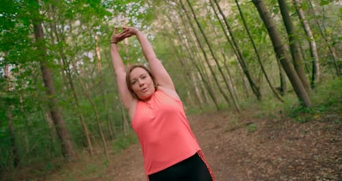 Caucasian woman doing exercise and hands stretching on warming up at outdoor workout in summer park.