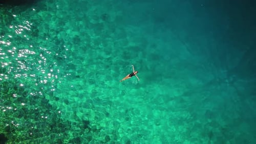The emerald waters of the Adriatic Sea envelop a solitary figure of woman swimmer off the coast of B