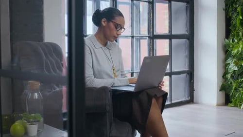 Jeune femme d'affaires noire prospère travaillant sur un ordinateur portable à Green Workspace