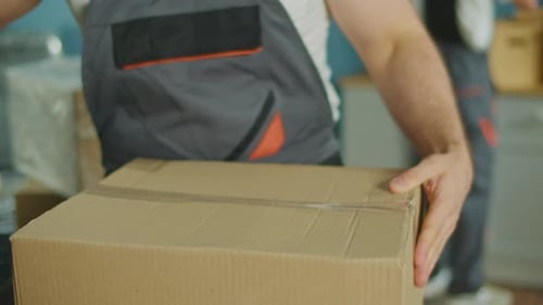 Worker of Moving Company Using Duct Tape Machine for Packing a Cardboard Box