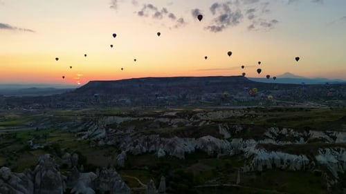 Hot Air Balloons Flying at Sunrise Over Landscape